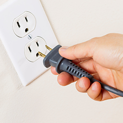 Inside Electric Lines, hand plugging cord into outlet