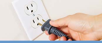 Hand plugging a cord into an electrical outlet