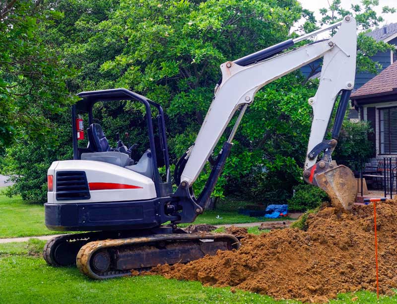 Backhoe digging in front of home