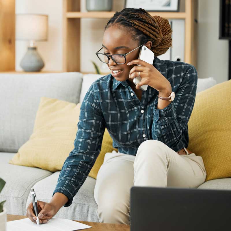 UtilityShield Enroll Online, woman on the phone while sitting on her couch